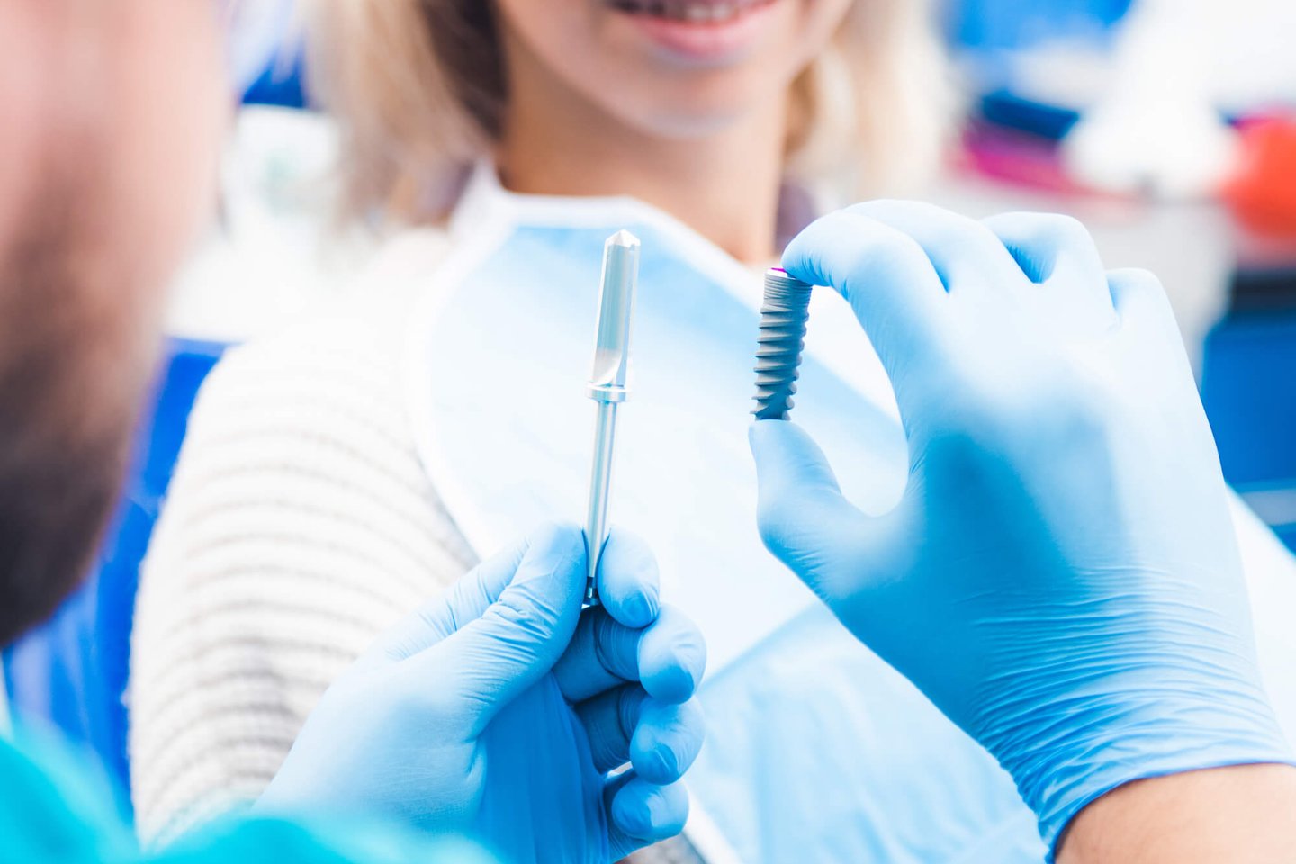 dentist showing patient a sample of dental implants winter park fl