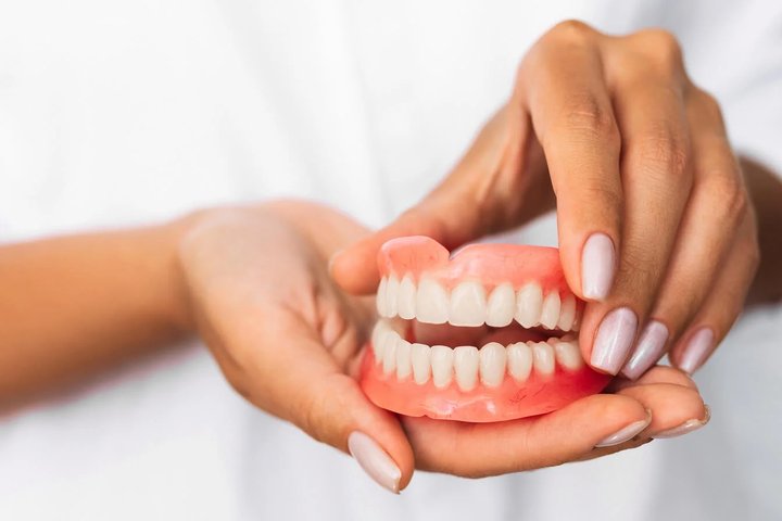Hands holding realistic dentures for fit dental implants in Orlando, FL