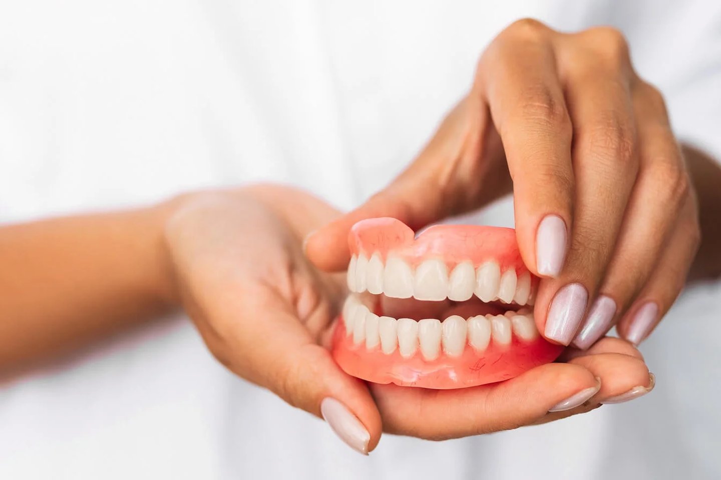 Hands holding realistic dentures for fit dental implants in Orlando, FL