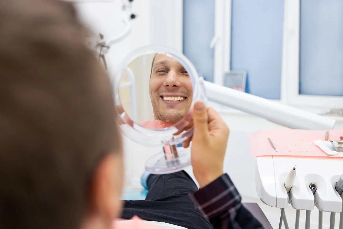 Man smiling in the mirror after getting dental implants in Orlando FL