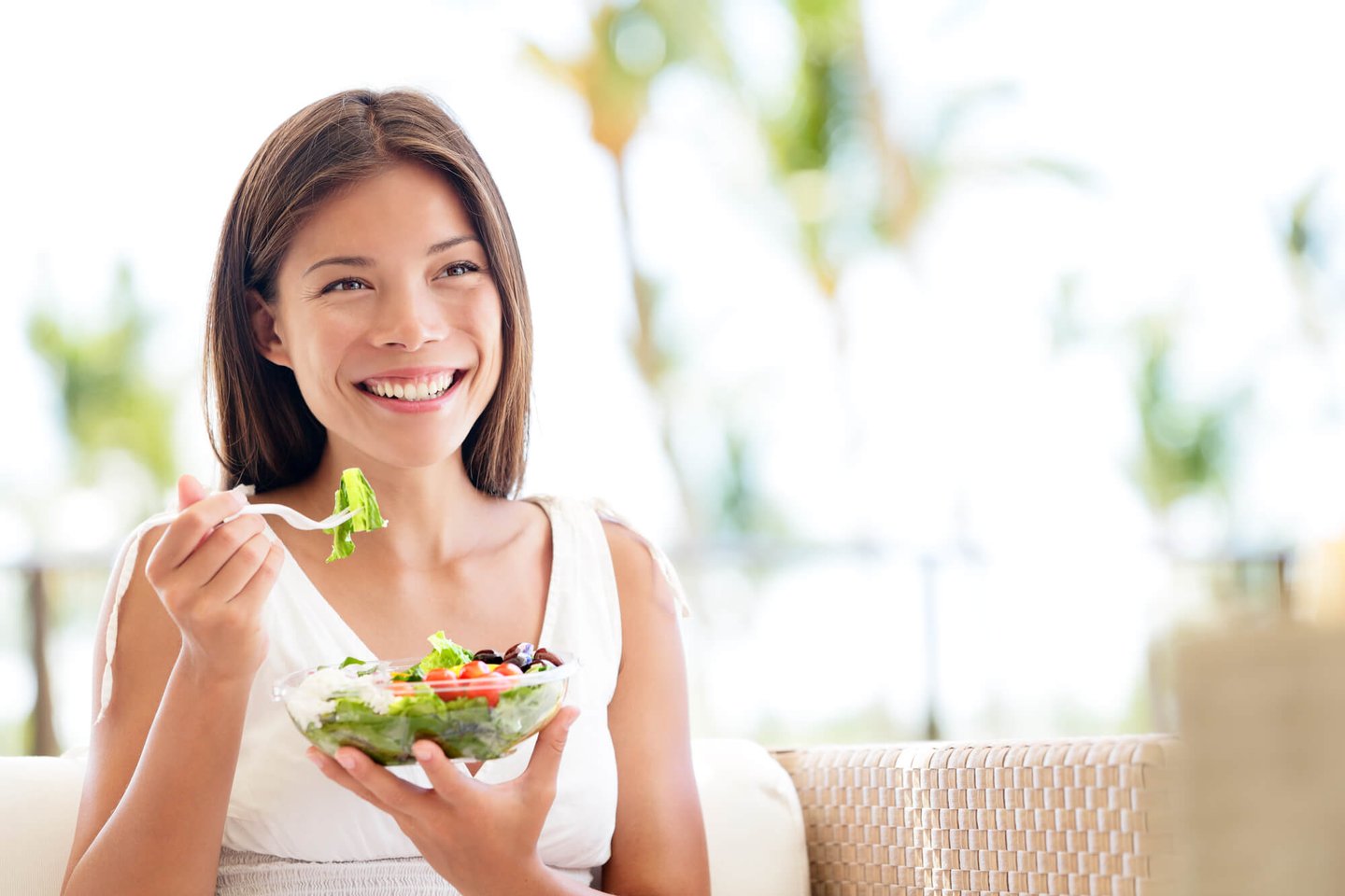 Asian woman eating a salad that's good for her dental implants