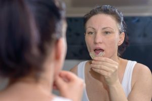 woman looks at mirror and outs on Invisalign in Winter Park